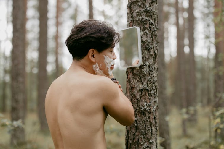 鏡を見ながら満足気にフェイスラインを確認する男性。清潔感があり、身だしなみを整えた雰囲気