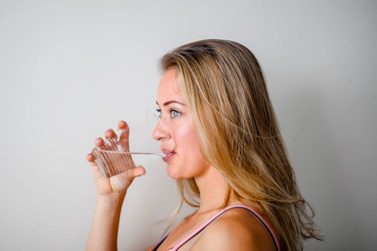 水を飲む女性のイメージ。施術前後の水分補給の重要性を表す健康的な写真