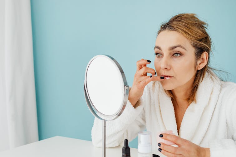 30代の女性が鏡で肌を確認しているイメージ。変化に気づき始めた表情
